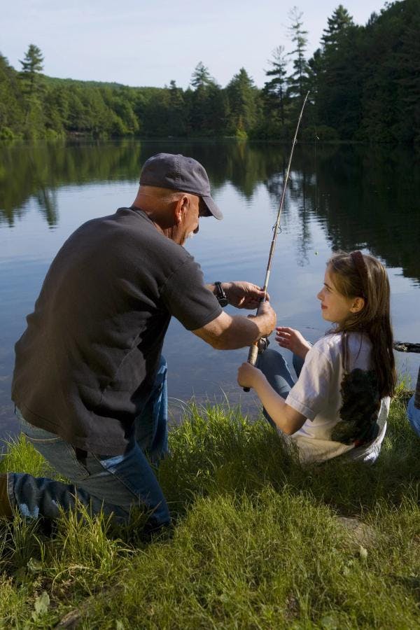 Parent teaching daughter to fish